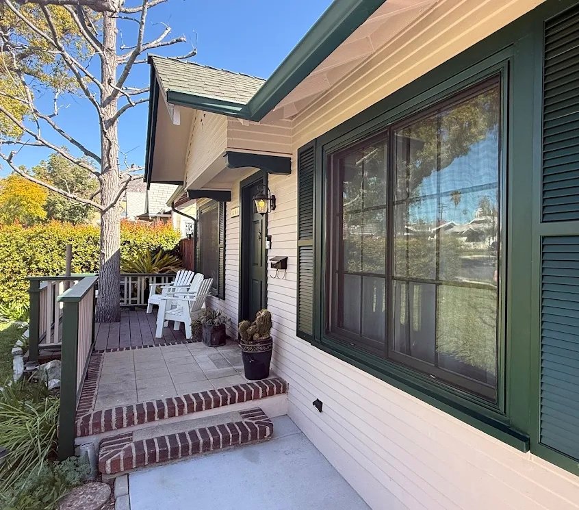 Cottage porch with deep green trim and brick steps